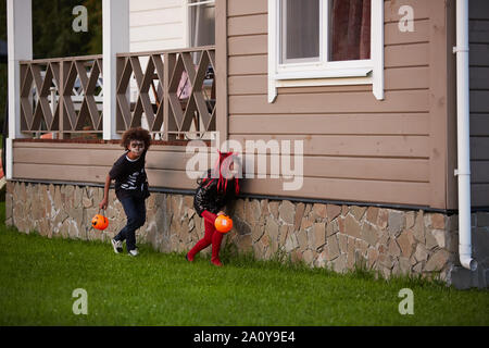 Zwei sneaky Kinder verstecken vor dem Haus während Süßes oder Saures auf Halloween, kopieren Raum Stockfoto