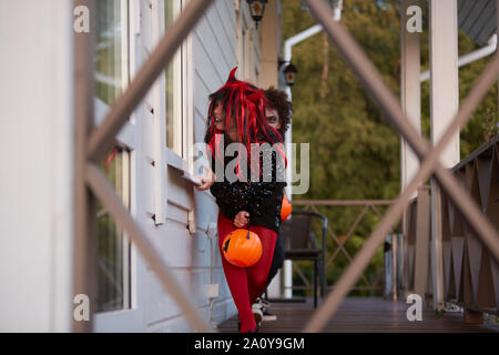 Porträt von zwei sneaky Kinder verstecken ausserhalb des Hauses beim Spielen auf Halloween, kopieren Raum Stockfoto