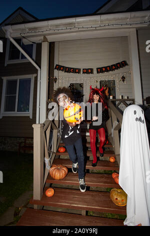 In voller Länge Porträt der aufgeregten Kinder verlassen Haus Trick oder das Behandeln auf Halloween, Schuß mit Flash Stockfoto