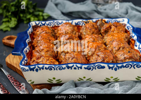 Fleischbällchen in saurer Sahne und Tomaten Sauce keramisch gegen einen dunklen Hintergrund, horizontale Ausrichtung Stockfoto