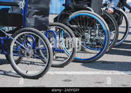 Rollstuhl Räder closeup auf Asphalt. Das Konzept der sozialen Gleichheit, Schutz und Unterstützung der Menschen mit Behinderungen Stockfoto