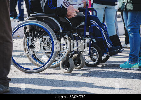 Rollstuhl Räder closeup auf Asphalt. Das Konzept der sozialen Gleichheit, Schutz und Unterstützung der Menschen mit Behinderungen Stockfoto