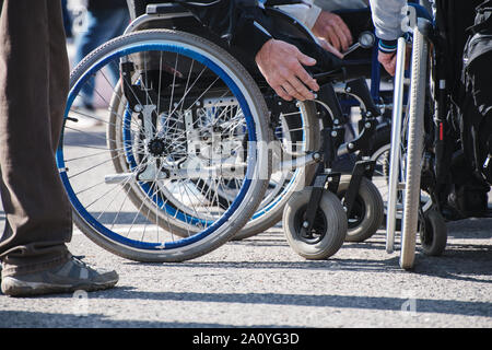 Rollstuhl Räder closeup auf Asphalt. Das Konzept der sozialen Gleichheit, Schutz und Unterstützung der Menschen mit Behinderungen Stockfoto