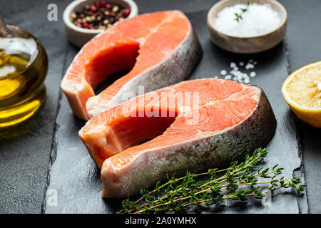 Lachssteaks, Gewürze und Kräuter zum Kochen auf schiefer Hintergrund. Rohen ungekochten Fisch Stockfoto