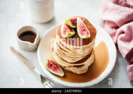 Pfannkuchen mit Feigen und Ahornsirup auf weiße Platte stack, grau konkreten Hintergrund. Leckeres Frühstück, Herbst Komfort Essen Stockfoto