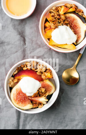 Feigen mit Müsli, Pfirsich und Joghurt. Gesunde Schüssel zum Frühstück. Ansicht von oben Stockfoto