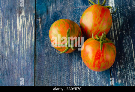 Rote Tomaten mit einem gelben Muster, natürliches Bio Tomaten auf einem Holztisch, Nahaufnahme Stockfoto