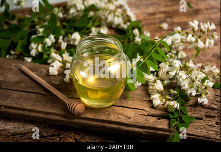 Honig in einem Glas mit akazienblüten auf einem Tisch Stockfoto