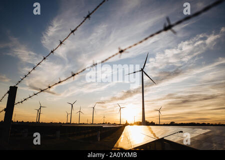 Stacheldraht, Windräder und Solarzellen auf einem Feld in Deutschland Stockfoto