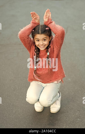 Frohe Ostern. Urlaub Bunny Girl posiert wie Kaninchen grauen Hintergrund. Kind lächelnd spielen Bunny Rolle. Verspieltes Baby feiern Ostern. Frühlingsferien. Talent und Handeln. Glückliche Kindheit. Cute Bunny. Stockfoto