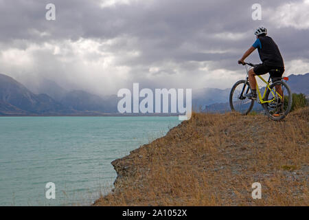 Radfahrer wieder ein Sturm über Aoraki/Mt Cook vom Ufer des Lake Pukaki auf die Alpen 2 Ocean Radweg Stockfoto