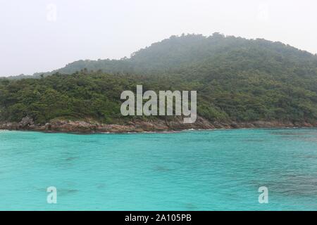 Tropische Insel, Blick auf die azurblaue Meer und Green Mountain mit Regenwald im Nebel bedeckt. Malerische Paradies Landschaft Stockfoto