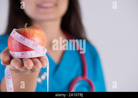 Gesunde Lebensweise, Ernährung und Sport Konzept. Close up lächelnd Arzt Frau hand Maßband um frisches Grün für Apple. Stockfoto