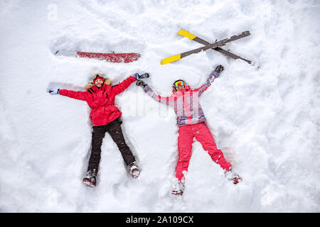 Skifahrer und Snowboarder liegen auf Schnee mit Ski und Snowboard und Spaß haben. Luftbild Stockfoto