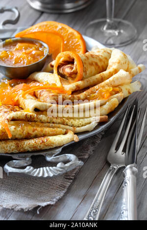 Crepes Suzette auf vintage Metallplatte auf Holztisch mit orange Sauce serviert, close-up auf einer Platte Stockfoto