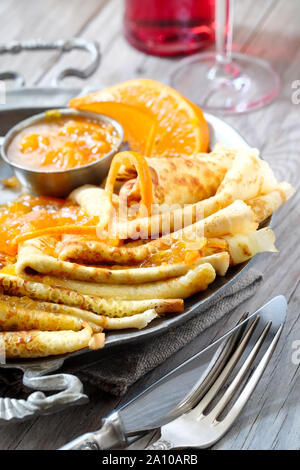 Crepes Suzette auf vintage Metallplatte auf Holztisch mit orange Sauce serviert, close-up auf einer Platte Stockfoto