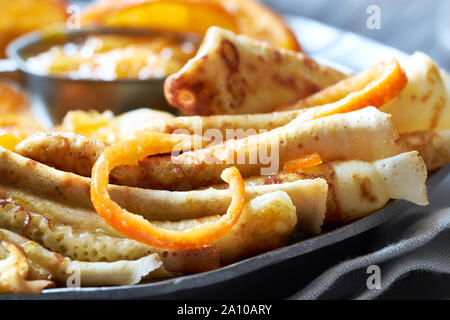 Crepes Suzette auf vintage Metallplatte auf rustikalen Bettwäsche mit orange Sauce serviert, horizontale Nahaufnahme Stockfoto