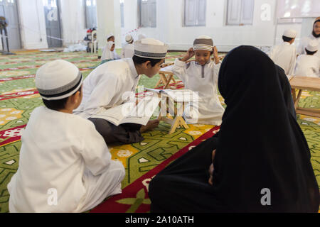 Ein jüngeres Malay Lehrer unterrichten einer Gruppe von Kindern im Inneren Masjid Moschee, Singapur Stockfoto