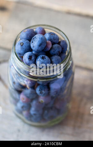 Blaubeeren in einem Glas auf einem Holztisch Stockfoto