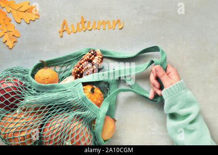 Herbst flach mit Türkis string Tasche mit orange Kürbisse, top vie am grauen Stein Hintergrund Stockfoto