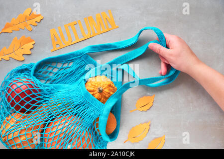 Herbst flach mit Türkis string Tasche mit orange Kürbisse, top vie am grauen Stein Hintergrund Stockfoto