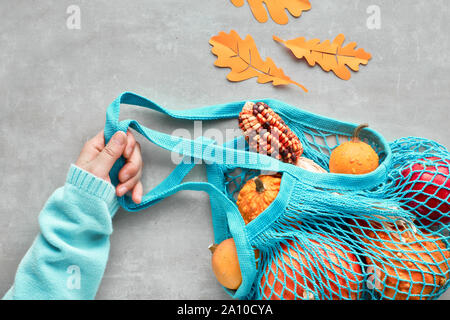 Herbst flach mit Türkis string Tasche mit orange Kürbisse, top vie am grauen Stein Hintergrund Stockfoto