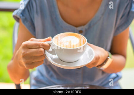 Hände halten weiß Kaffeetasse mit Untertasse. Stockfoto