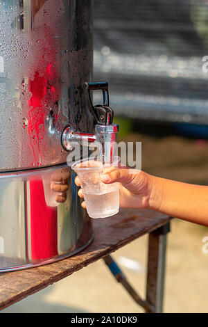 Hand junge Holding das Glas mit Wasser aus dem Kühler. Stockfoto