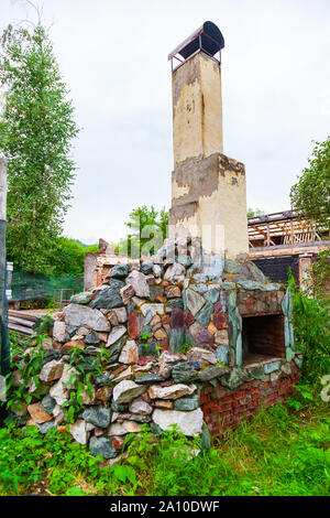 Alten Armen zerstört Kamin stehen auf der Straße mit Brennholz innerhalb, nach der Zerstörung des Gebäudes. Stockfoto