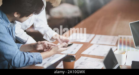 7/8-Ansicht von UI-Designer Hobeln der UX-Anwendungsentwicklung mit Teammitgliedern in modernen Arbeitsplatz Stockfoto