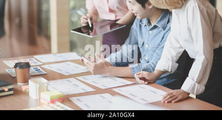 7/8-Ansicht von UI-Designer Hobeln der UX-Anwendungsentwicklung mit Teammitgliedern in modernen Arbeitsplatz Stockfoto