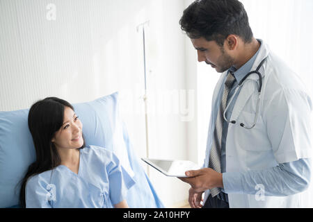 Arzt ist im Gespräch mit jungen weiblichen Patienten und sich Notizen während in seinem Büro. Stockfoto