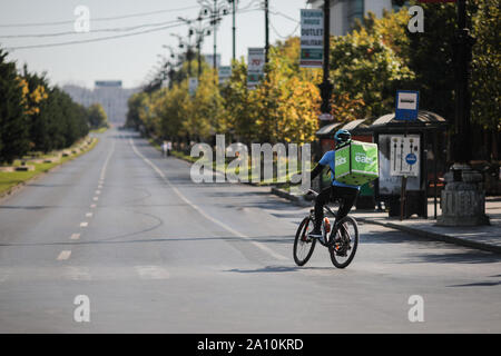 Bukarest, Rumänien - 22. September 2019: UBER isst Lieferung Biker auf einem leeren Boulevard an einem sonnigen Tag. Stockfoto