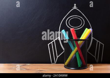 Schule Schreibwaren Bürobedarf und Hand gezeichnet Rakete auf dunklem Hintergrund. Zurück zum Konzept der Schule. Neue Idee und Kreativität starten Stockfoto