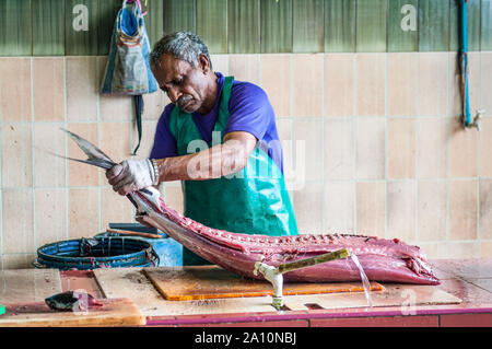 Male, Malediven - November 16, 2017: der Mann, der die großen Thunfischen für den Verkauf auf dem Fischmarkt in der Stadt und der Insel Male, die Hauptstadt der Malediven. Stockfoto