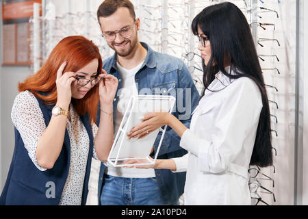 Rothaarige client setzen auf Ned moderne Gläser, schauen in den Spiegel bei Store, Geschäftskonzept. Bis schließen Foto Stockfoto