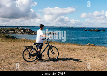 Attraktive junge männliche Fahrten mit dem Fahrrad genießen Sie die Aussicht auf die Landschaft auf der Insel Batz Stockfoto