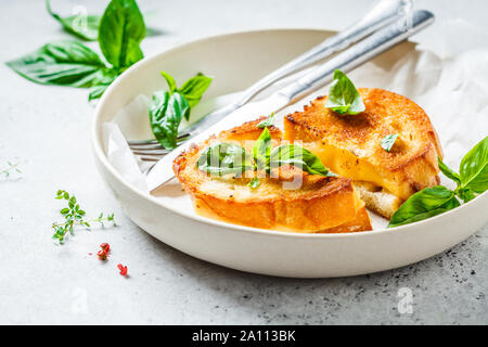 Gebratene Sandwiches mit Käse und Basilikum auf einem weißen Teller. Stockfoto