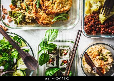 Gesund vegan Essen in Glasbehältern. Flach Eintopf mit Kichererbsen, vegan bergrer, Hummus, kale Salat, vegane Sushi Brötchen und Brot. Stockfoto