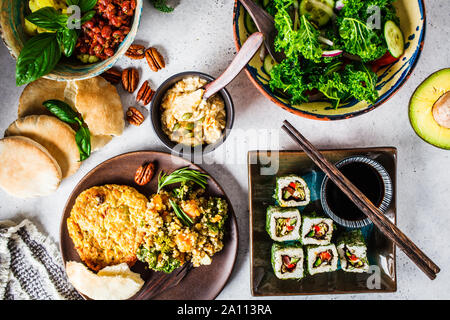 Gesunde vegane Lebensmittel Tabelle. Flach Eintopf mit Kichererbsen, vegan bergrer, Hummus, kale Salat, vegane Sushi Brötchen und Brot. Stockfoto