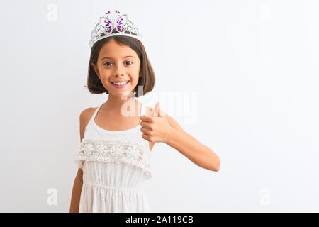 Schönes kind Mädchen mit Princess Crown stehend über isoliert weißer Hintergrund tun glücklich Daumen nach oben Geste mit der Hand. Die Genehmigung der Ausdruck suchen Stockfoto