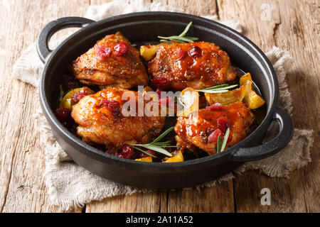 Urlaub Essen warm gebackene Hühnerkeule mit Äpfeln, Preiselbeeren und Rosmarin closeup in einer Pfanne auf dem Tisch. Horizontale Stockfoto