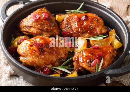 Hähnchen Schenkel mit karamellisierten Äpfeln, Preiselbeeren und Rosmarin close-up in einer Pfanne auf dem Tisch. Horizontale Stockfoto