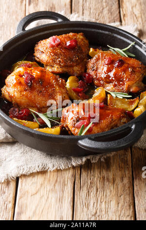 Lecker würzigen Hähnchen Schenkel gebacken mit Äpfeln, Preiselbeeren und Rosmarin close-up in einer Pfanne auf dem Tisch. Vertikale Stockfoto