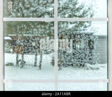 Winter Fenster, Wassertropfen und Schneeflocken auf einer Fensterscheibe. Stockfoto