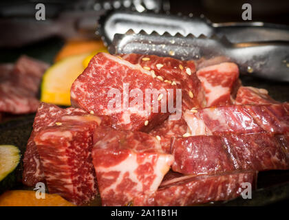 Frisches rot Rindfleisch bereit für Grill Grill yakiniku mit Sesam und Tong. Stockfoto