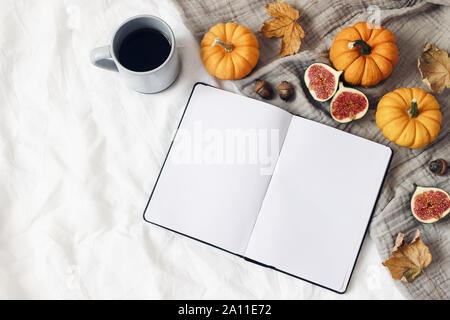 Herbst das Frühstück im Bett. Leere öffnen Notebook mockup. Tasse Kaffee, bunte Blätter, Feigen und wenig orange Kürbisse. Weiße Bettwäsche Hintergrund. Thanksgi Stockfoto