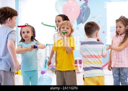 Große Gruppe der Kinder im Alter von 3 bis 5 in Club auf eine Geburtstagsfeier blasen Krachmacher Hörner und Twisted pfeift Stockfoto