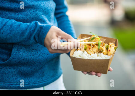 Die Hände des jungen Mann mit Mittagessen in einem Feld von Recyclingpapier Stockfoto