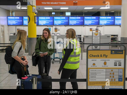 Katie O'Mara (links) und Maddison Millar (Mitte) sprechen Sie mit Regierung Mitglied des Personals vor leeren Thomas Cook Check-in-Schalter am Flughafen Gatwick in Sussex, wie die 178-jährige Tour Operator hat den Handel mit sofortiger Wirkung eingestellt, nachdem man ein abschließendes Angebot ein Rettungspaket von Gläubigern zu sichern. Stockfoto